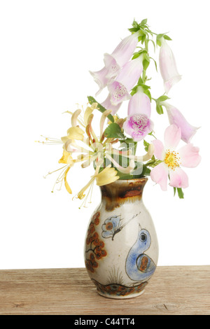 Arrangement of wild flowers in a decorated pot on a wooden bench Stock Photo