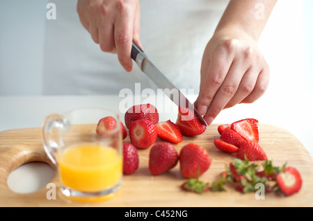 Woman slicing strawberries on wooden chopping board Stock Photo