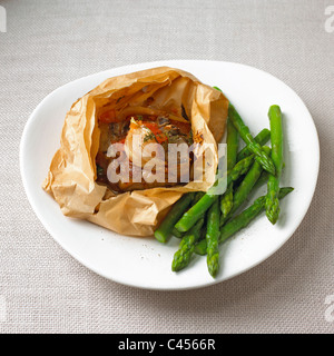 Lamb chops in paper with asparagus on plate, close-up Stock Photo