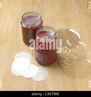 Jars of raspberry jam with waxed paper discs and cellophane covers, close-up Stock Photo