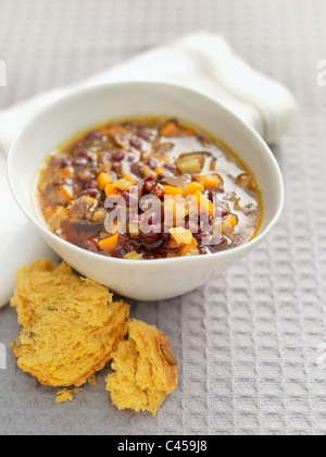 Bowl of adzuki bean vegetable soup served with bread, close-up Stock Photo
