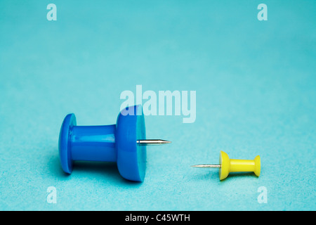 Yellow and blue thumb tack on blue background Stock Photo