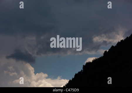 Dark storm clouds over forest and mountains in background Stock Photo ...