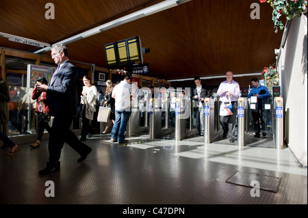 Commuters pass through a ticket barrier on a sunny morning at Oxford Road railway station in Manchester. Stock Photo