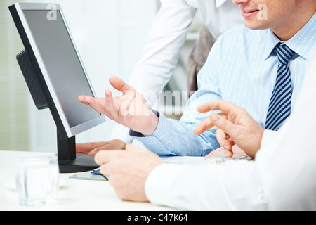 Image of young businessman hand pointing at computer monitor while making presentation Stock Photo
