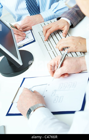 Image of human hands working with papers and typing on keyboard Stock Photo