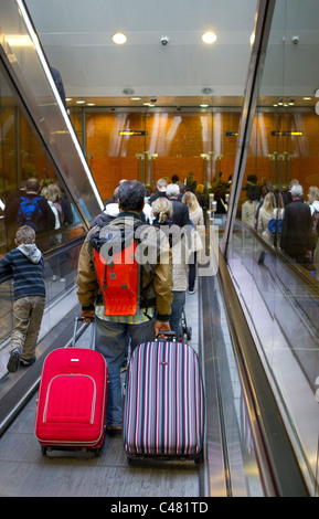 man with luggage on escalator Stock Photo