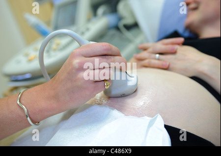 pregnant woman on patient consulting table having ultrasound scan by female doctor Stock Photo