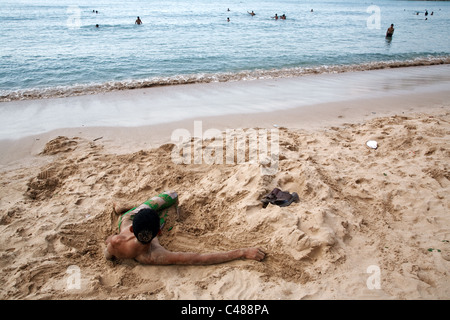 A young Yemeni man lying in the sand on the beach on the coast of Red Sea in Aden, Yemen. Stock Photo