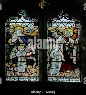 A stained glass window by The Kempe Studios depicting the Holy Family's Flight into Egypt, accompanied by angels Stock Photo