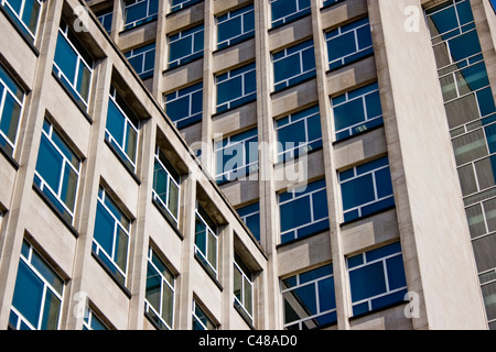 Windows of a concrete office block reflect a blue sky. Stock Photo