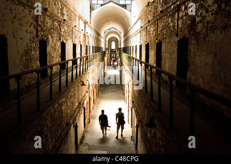 Tourists walk down a crumbling cellblock at Eastern State Penitentiary in Philadelphia, Pa. The prison is said to be haunted. Stock Photo