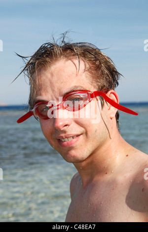 Model released man on summer holiday wearing a pair of red swimming goggles Stock Photo