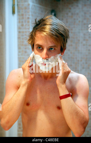 Model released man in the bathroom shaving his face applying shaving cream Stock Photo