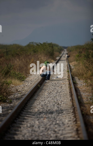 A Central American migrant traveling across Mexico to work in the United States waits along the railroad to jump a train, in Ixt Stock Photo