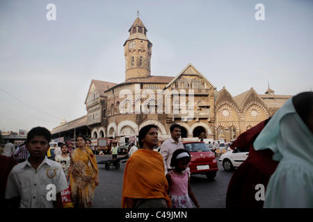 People walk along a crowded street in india with an ornate building in the background. Stock Photo