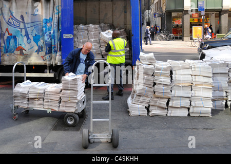 Street scene men unloading lorry load of Evening Standard free newspapers from truck parked Liverpool Street train station City of London England UK Stock Photo