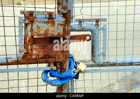Padlock and chain around entrance gates to disused premises concept image for subjects including redundancy closure locked out run down obsolete Stock Photo