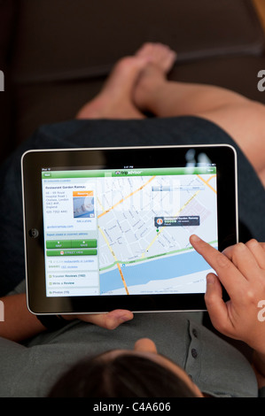 close up of woman using iPad digital tablet computer to read restaurant review in London using Tripadvisor app Stock Photo