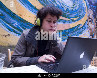 College student works on her computer in a cafe garden in Brooklyn, New York. Stock Photo