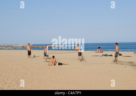 A group of men friends having fun playing beach-tennis on a beach in Barcelona, Spain Stock Photo