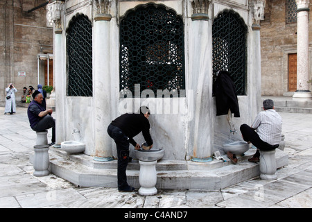 Men washing their feet in the courtyard of the Mosque of the Valide Sultan, the Yeni Cami also known as the New Mosque, Istanbul Stock Photo