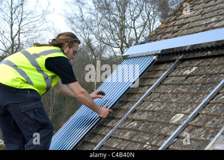 Engineers installing solar thermal evacuated tube array on the roof of ...