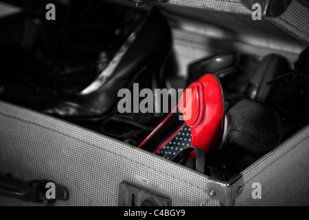 Colour popped image of womens shoes in old fashioned army demob suitcase with red shoe in colour Stock Photo