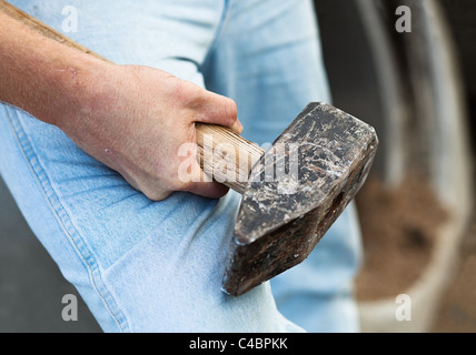 Male hand holding large heavy hammer; selective focus Stock Photo