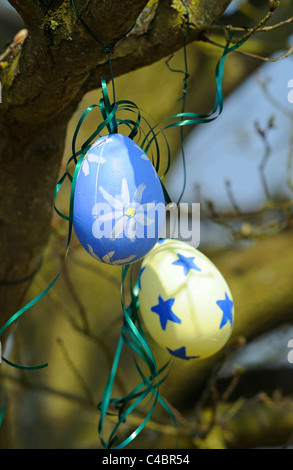 Brightly decorated polystyrene eggs or Easter eggs hanging from trees on coloured ribbons Stock Photo