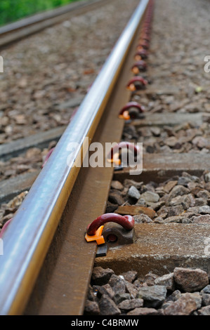 Steel rail tracks held in position with spring loaded clips mounted onto concrete sleepers Stock Photo