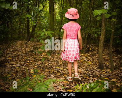 Girl in pink walks through woods Stock Photo
