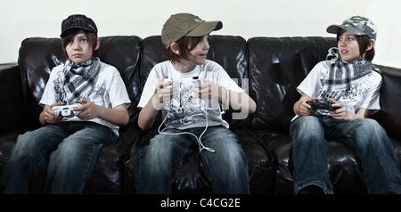 Three views of the same boy playing computer games on PS3 Xbox 360 and Wii Stock Photo