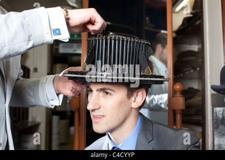 Man with conformateur device on head whilst having head measured for Silk Top Hat at Lock & Co hatters,London.Photo:Jeff Gilbert Stock Photo