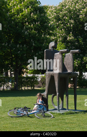 A German university student studies at the base of a sculpture in the park outside of the Alte Pinakothe art museum in Munich. Stock Photo