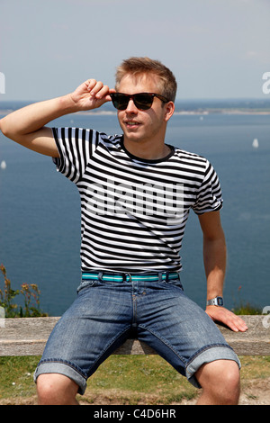 Man wearing striped T shirt on holiday wearing sunglasses relaxing and having a rest enjoying the sun - Model Released Stock Photo