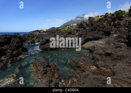 A panoramic view of a saltwater natural swimming pool in São João, Pico island, Azores, overlooking Pico mountain Stock Photo