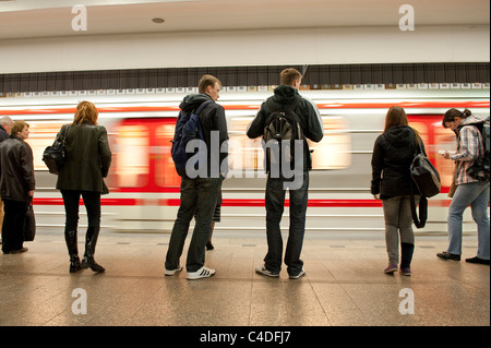 Passengers wait as an underground train pulls in at Dejvika Metro station on the Prague Metro Stock Photo