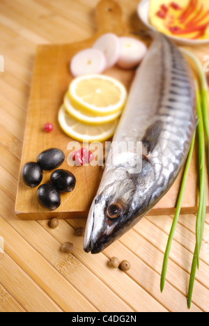 Fresh mackerel with olives, lemons and onions over wooden chopping board Stock Photo
