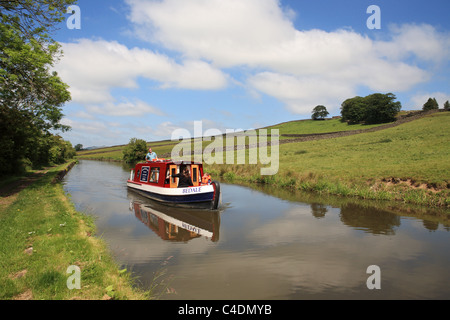 A family on a canal narrowboat glides along the Leeds and Liverpool canal near to Skipton, North Yorkshire, England, UK Stock Photo