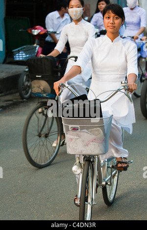 Student in Ao Dai dress cycling home from school Stock Photo