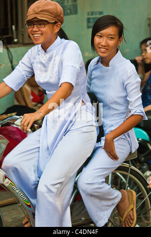 Two students in Ao Dai dress on bicycle Stock Photo