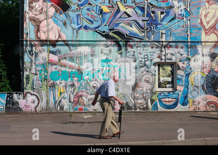 A pedestrian walks past a building covered with graffiti painting in the city of  Leipzig in Eastern Saxony Eastern Germany Stock Photo