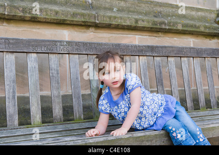 Four years old girl sitting on the wooden bench Stock Photo