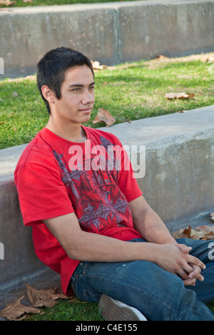 15-18 year old olds Young man. Blackfoot American Native American meditating prayerful thoughtful dreaming thinking sitting alone park. MR © Myrleen P Stock Photo