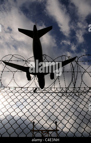 A landing plane crossing the barbed wire perimeter fence at Heathrow Airport Stock Photo