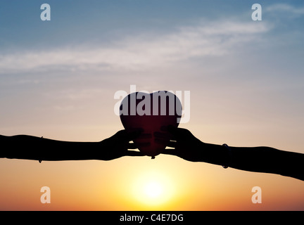 Indian girls hands holding a heart shaped balloon. Silhouette Stock Photo