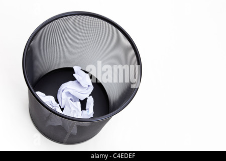 Black metal mesh wastepaper bin with screwed up pieces of paper in the bottom isolated on a white background seen from above Stock Photo