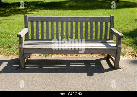 A park bench in a sun-drenched Hyde Park, London. Stock Photo