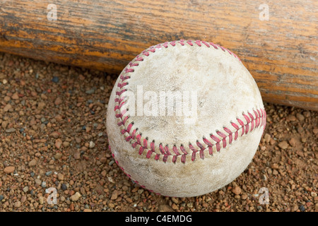 An old worn baseball and bat on a baseball field Stock Photo